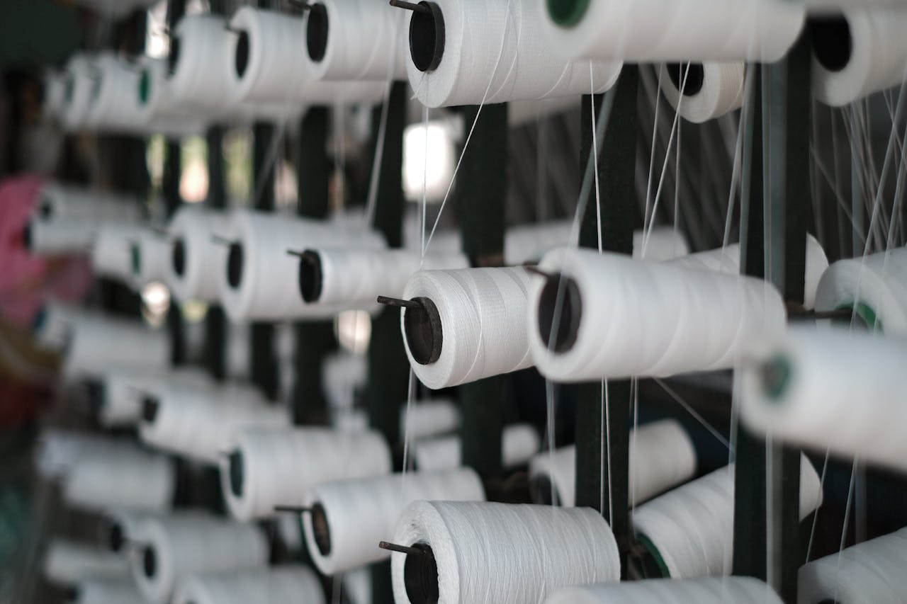 The Nuda Project Close-up of white sewing threads on spools, showcasing textile production in Vietnam.